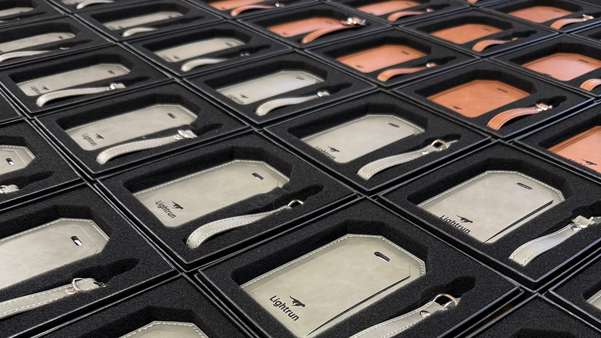 Collection of gray leather luggage tags with 'Lightrun' branding in black display cases.