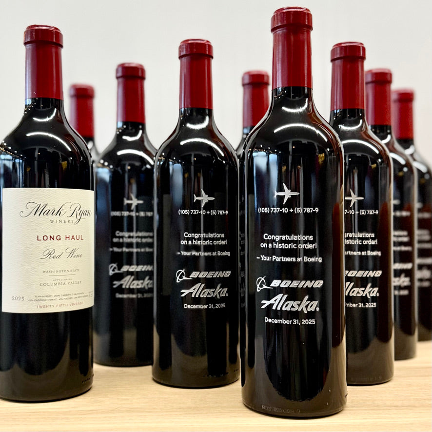 Row of wine bottles with branded labels on a wooden surface