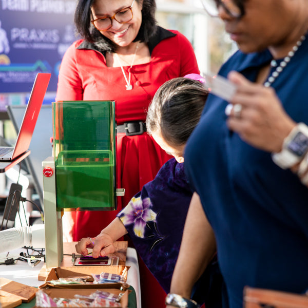 People interacting with onsite engraving at a gala event.