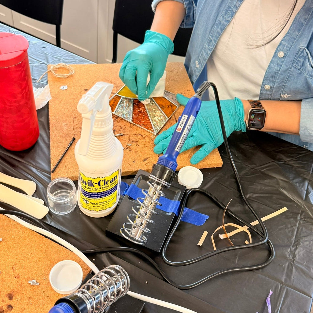 Hands working with colorful glass pieces during a guided stained-glass workshop in Renton, Washington.