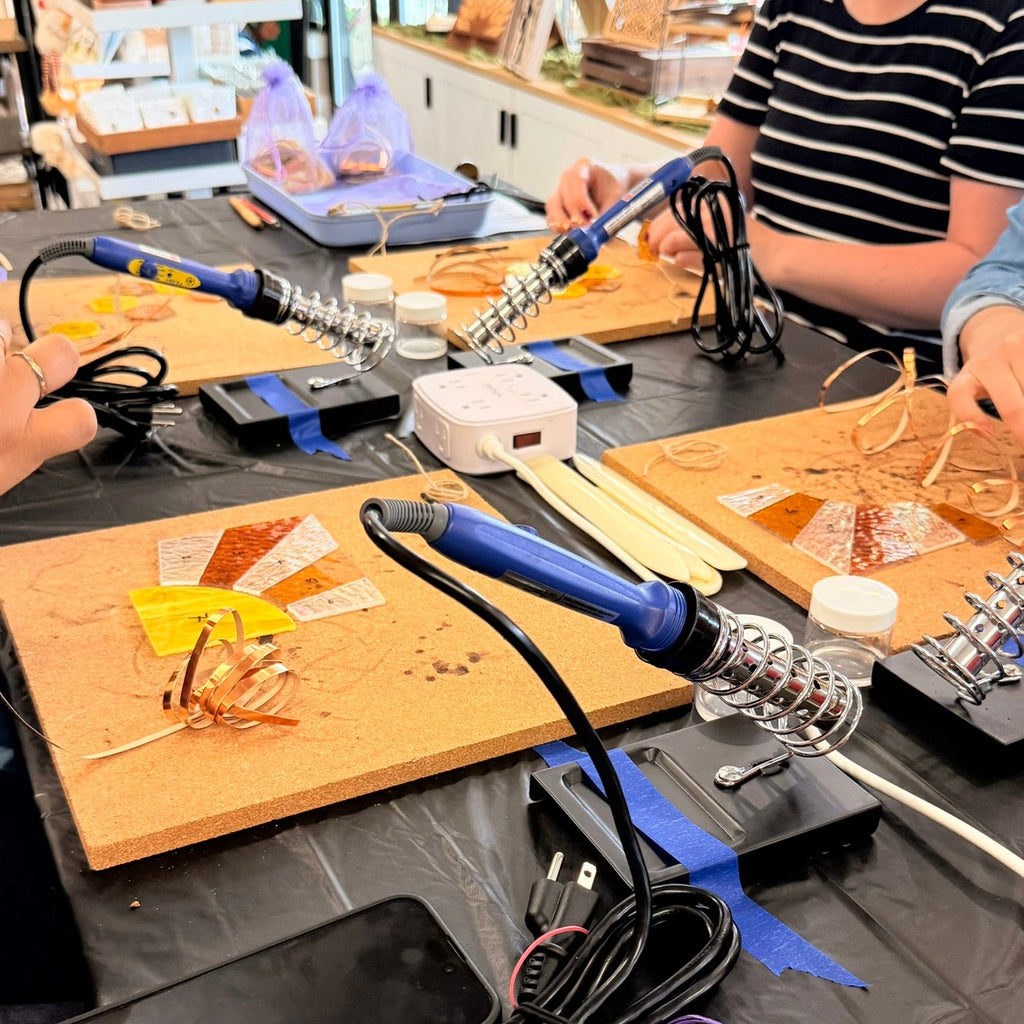 Students creating handmade stained-glass art during a beginner-friendly workshop at Foxwood Engraving.
