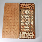 Artisan-made wooden Fanorona board with handcrafted playing pieces.