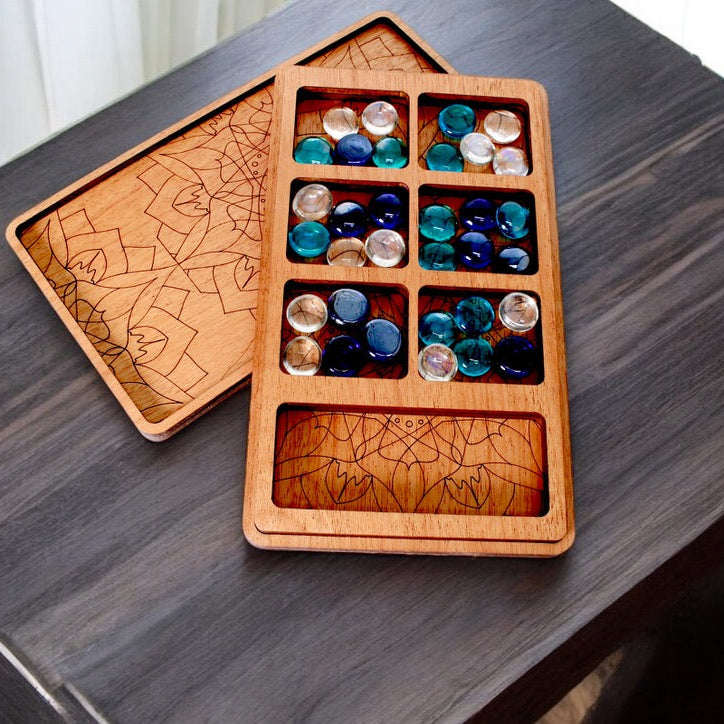 Artisan wooden Mancala game with colorful glass stones and engraved tray.