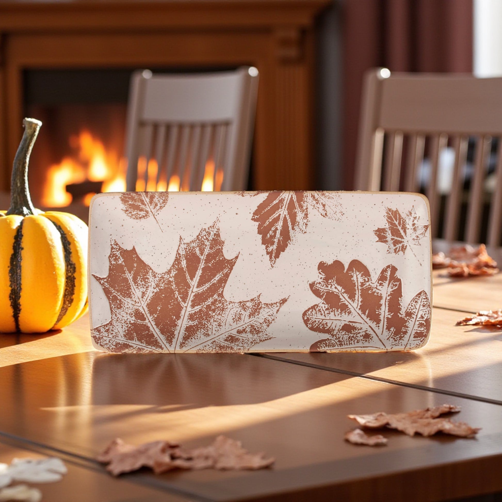 Cream ceramic platter with debossed fall leaf pattern.