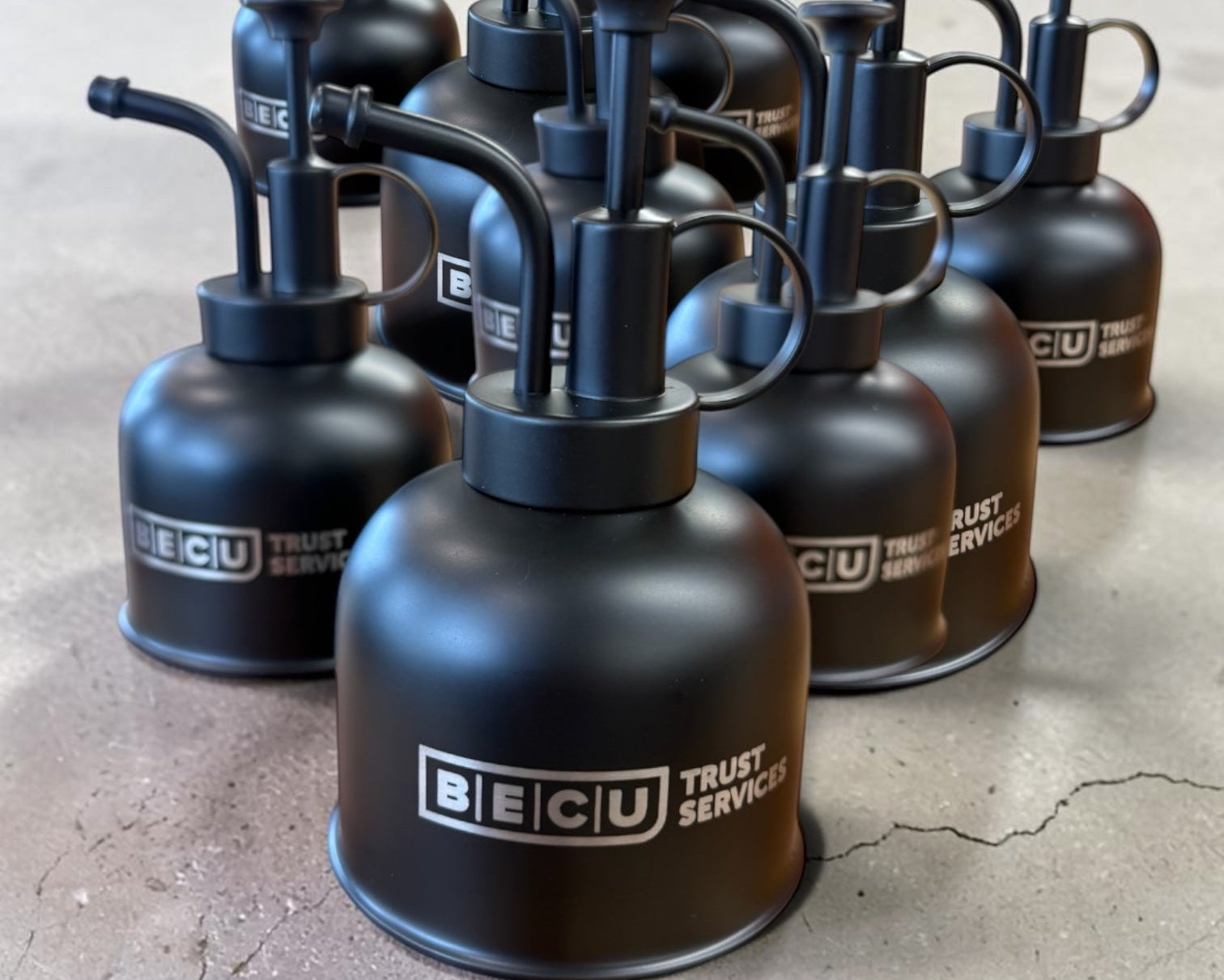 Batch of black BECU-branded plant misters personalized by Foxwood Engraving

