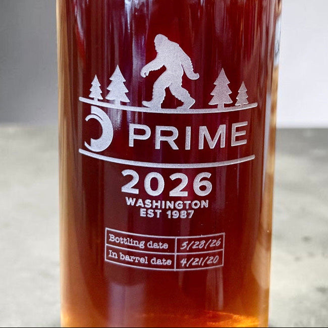 A close-up of a dark amber glass bottle etched with a logo