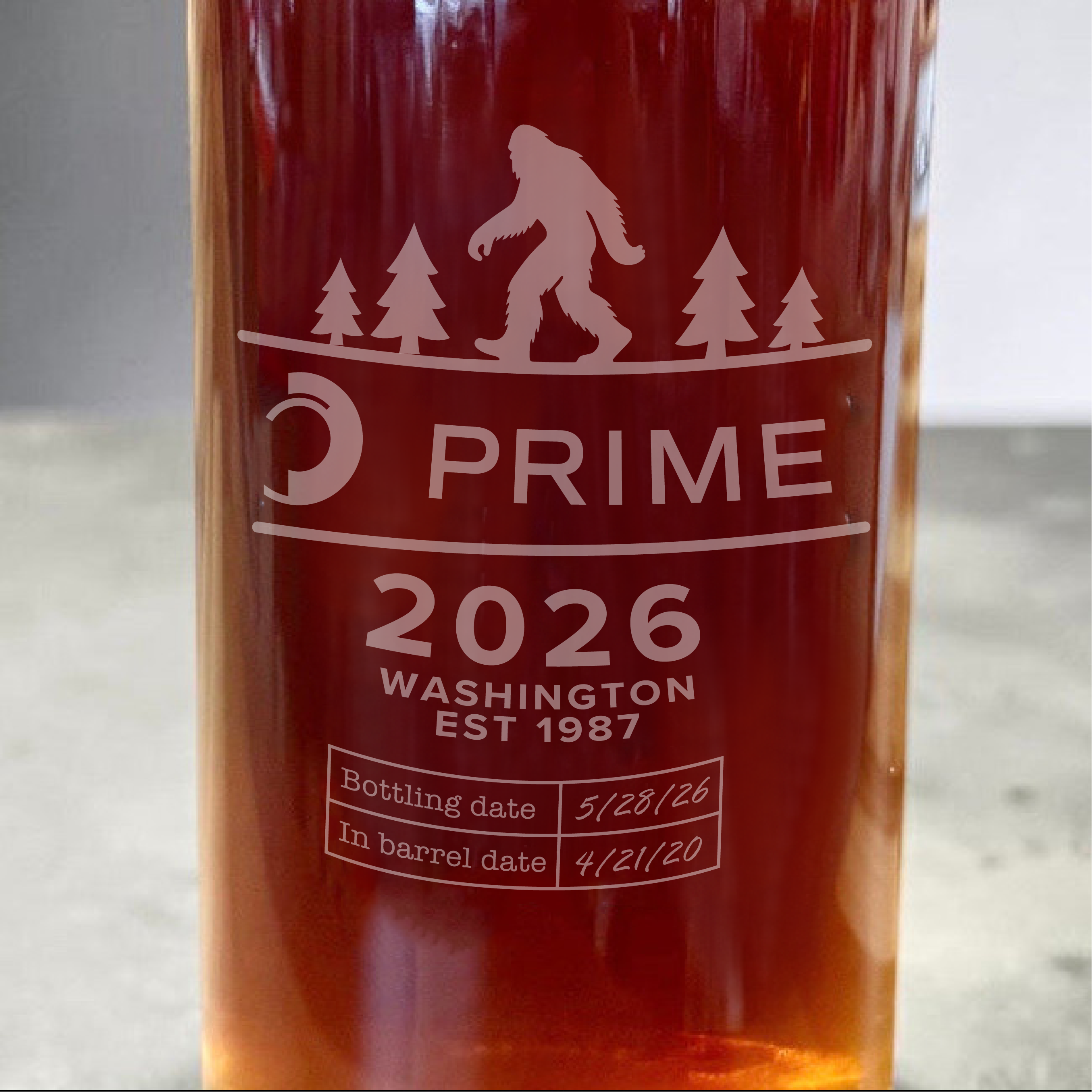Close-up of a dark amber glass bottle with frosted custom laser engraving 