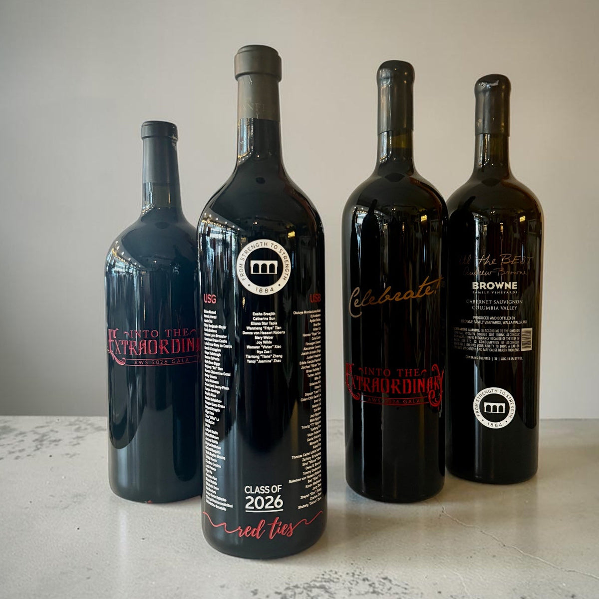 Four dark wine bottles personalized with detailed commemorative artwork, names and milestone information.