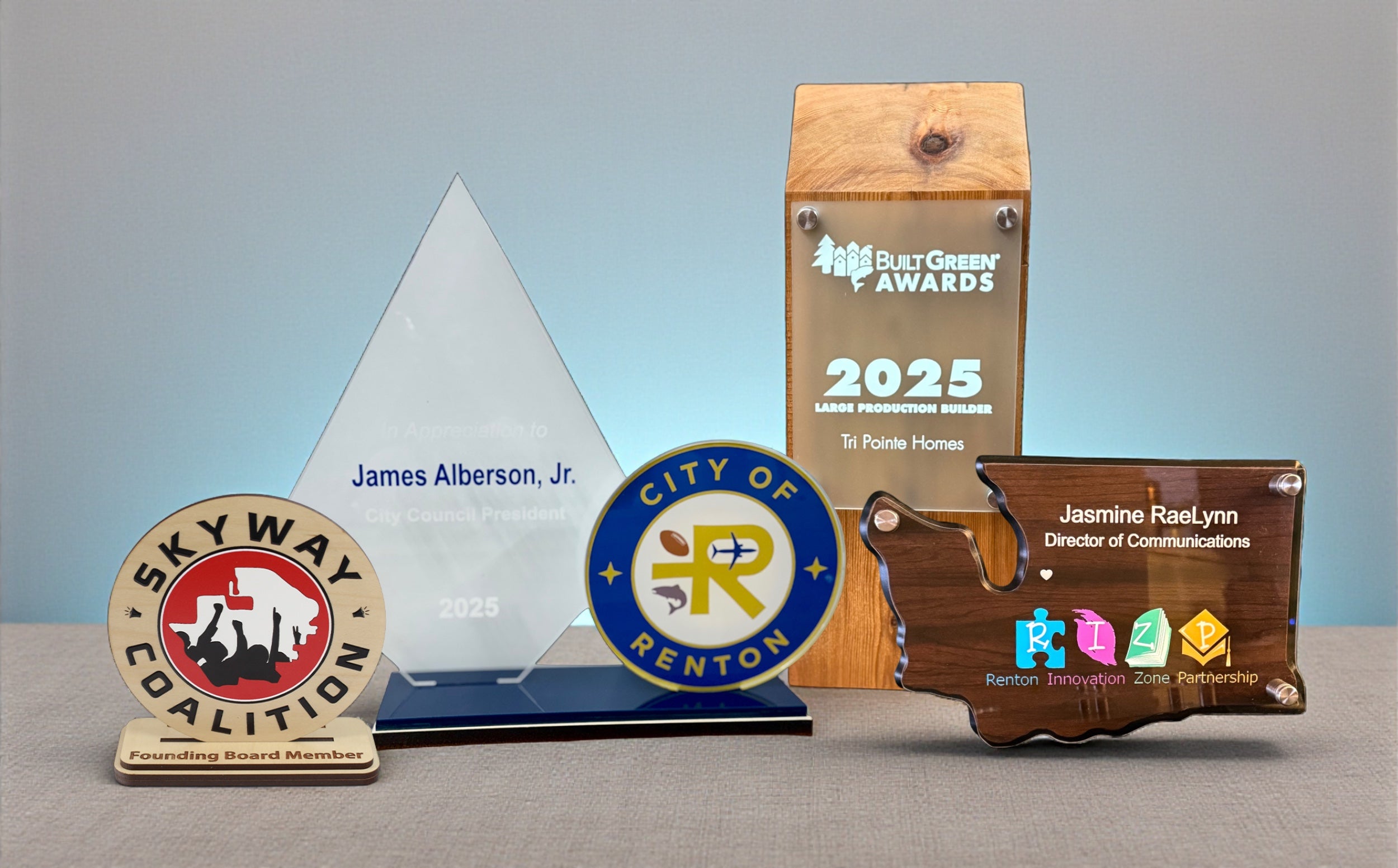 Collection of custom corporate awards in wood, acrylic and mixed materials, including recognition plaques and personalized presentation pieces