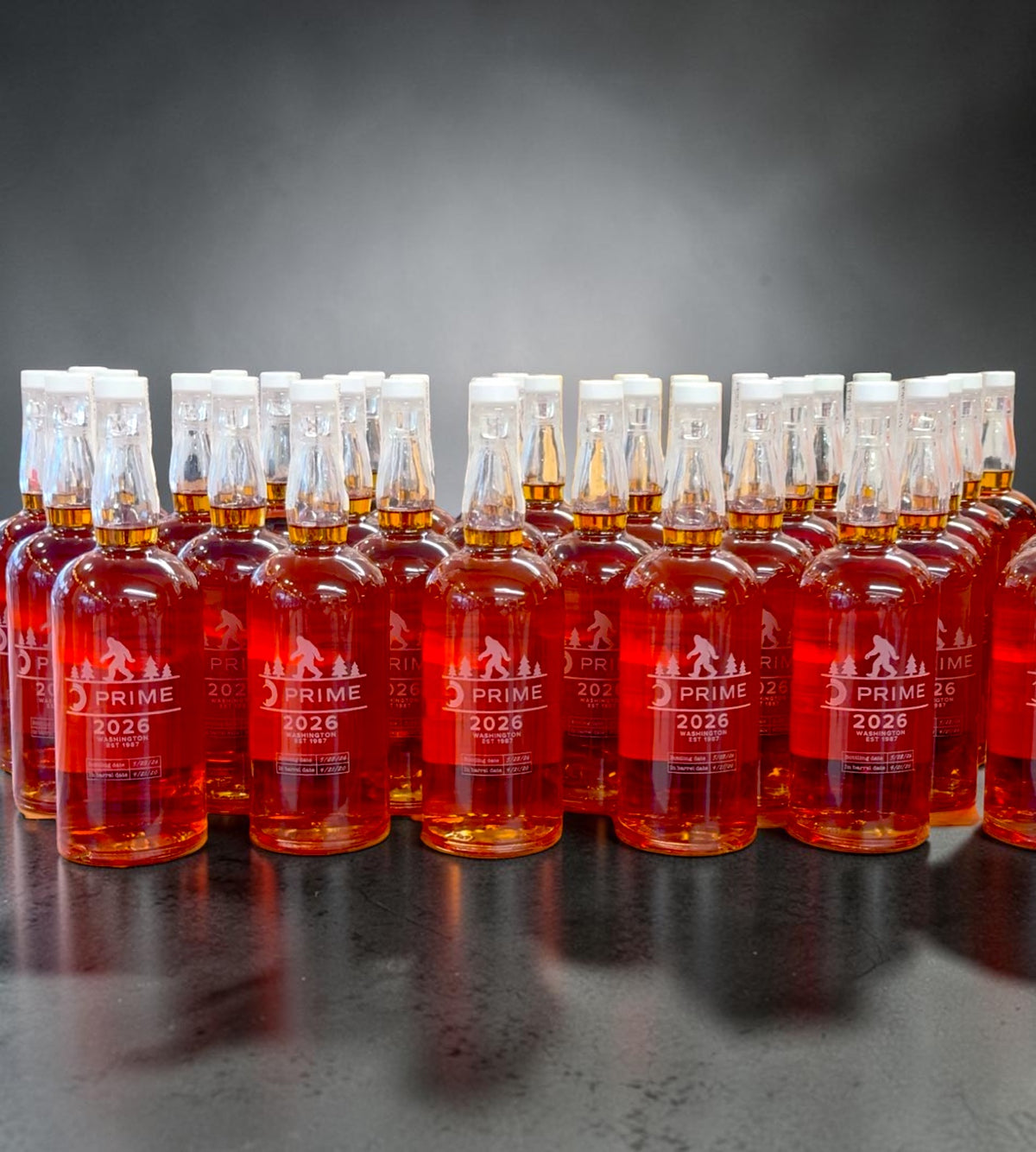 Custom engraved whiskey bottles for corporate events using precision rotary laser engraving on glass bottles.