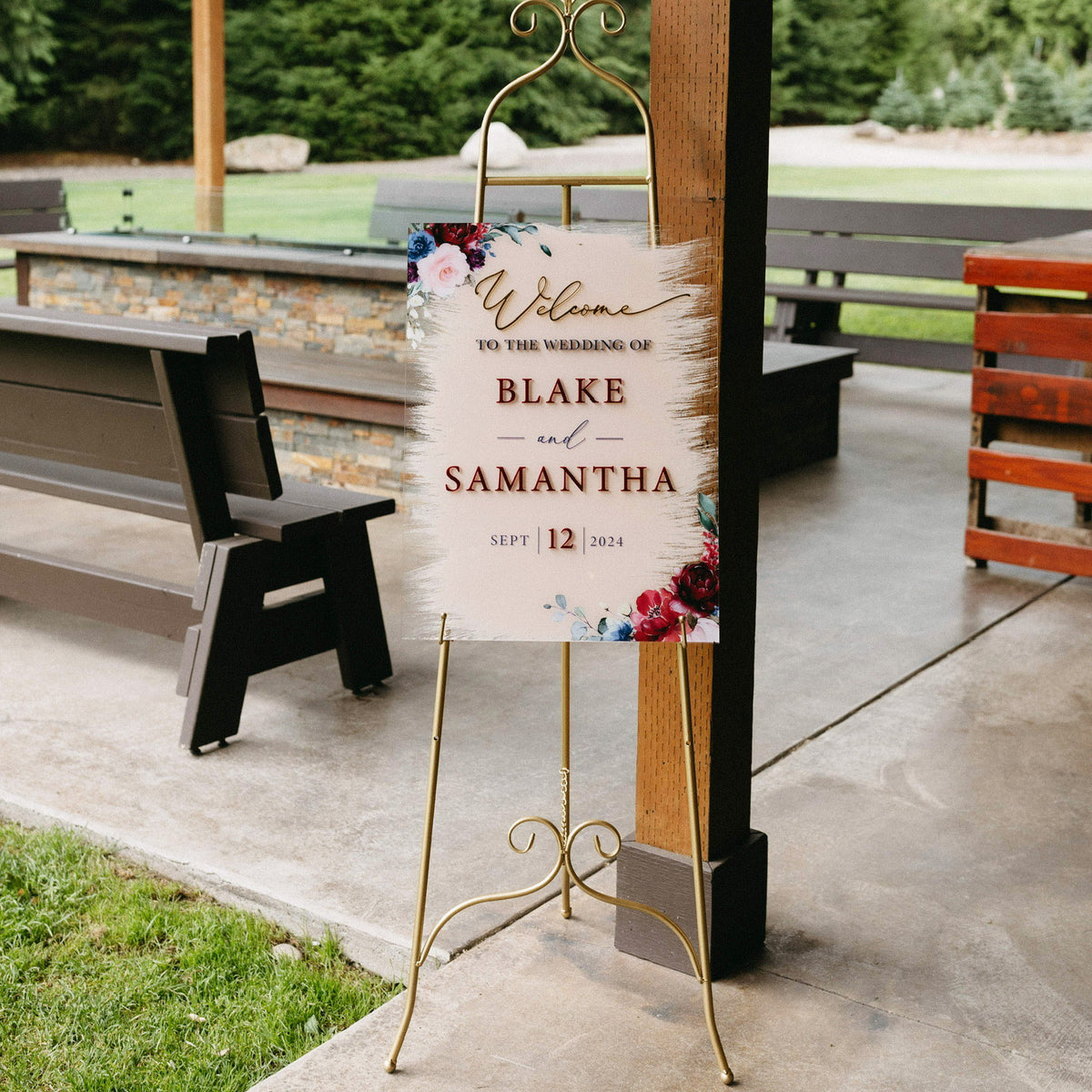 Custom floral wedding welcome sign for Blake and Samantha displayed on a gold easel at an outdoor venue.