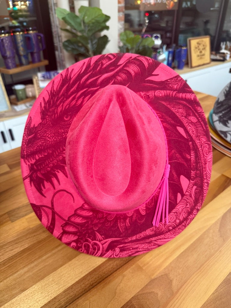 Bright pink felt cowboy hat personalized with an intricate laser-engraved feather design.