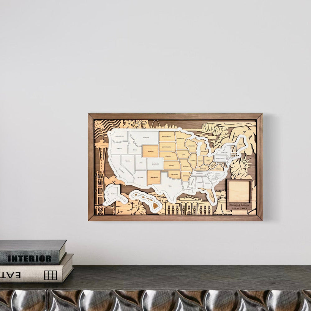 Wooden map of the United States on a wall above a shelf with books.