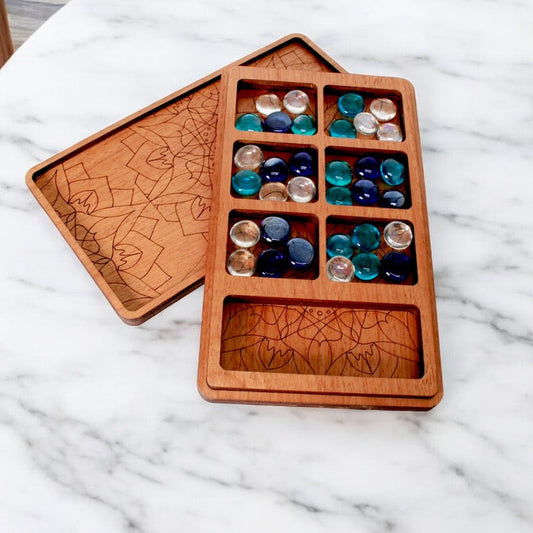 Handcrafted wooden Mancala board with engraved lid and glass stones.