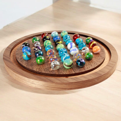 Handcrafted wooden marble solitaire game board with colorful marbles.