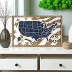 Wooden framed map of the United States with a personalized nameplate on a wall above a desk.