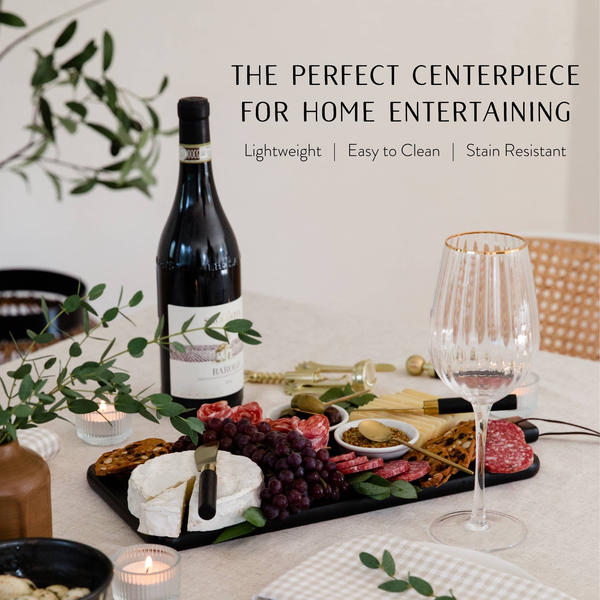 Wine bottle, charcuterie board with food, and glass on a table with text about the perfect centerpiece for home entertaining.