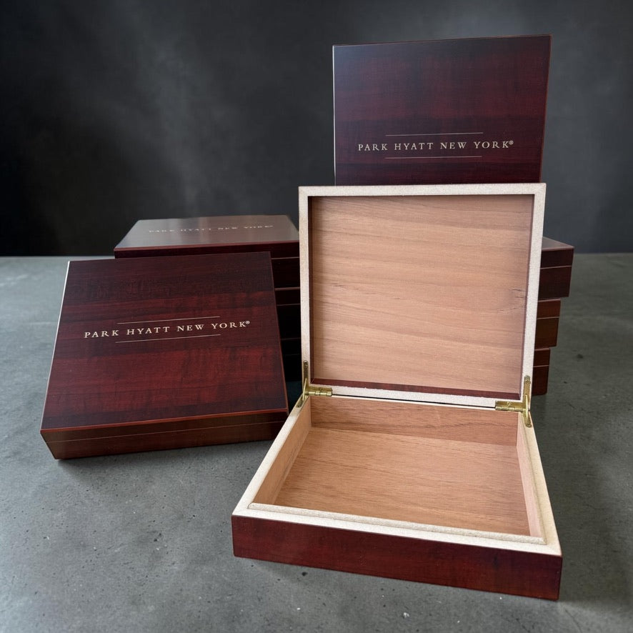 Custom wood keepsake boxes engraved with the Park Hyatt New York logo, including one open box showing its cedar-lined interior.