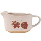 Rustic ceramic gravy pitcher with autumn leaf motif and bare base.