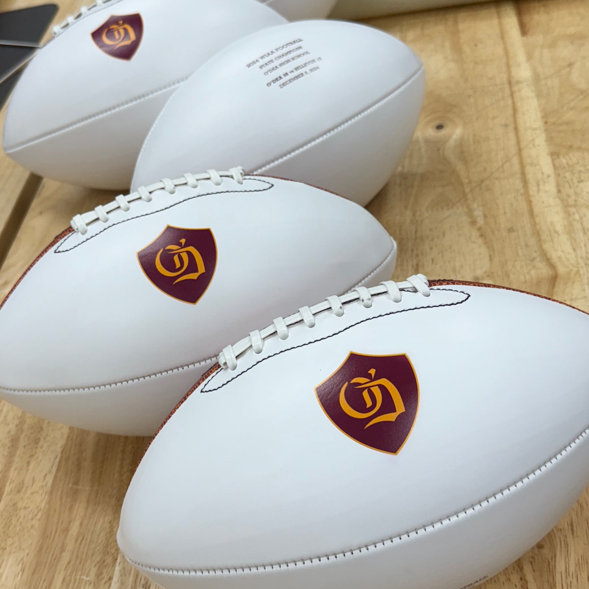 White promotional footballs UV printed with a full-color shield logo.