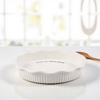 Simple white stoneware pie dish with debossed text inside rim.