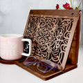 Wooden book stand with engraved front panel and coffee mug beside reading tray