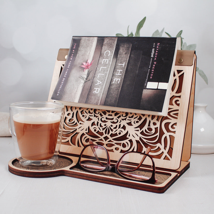 Wooden reading valet holding an open book with coffee mug nearby